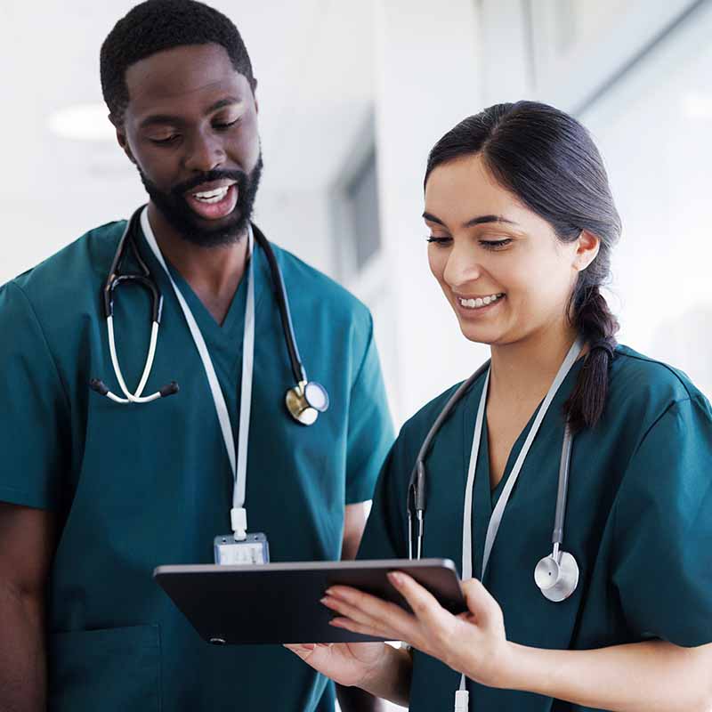 Two nurses conferring about patients on an ipad.