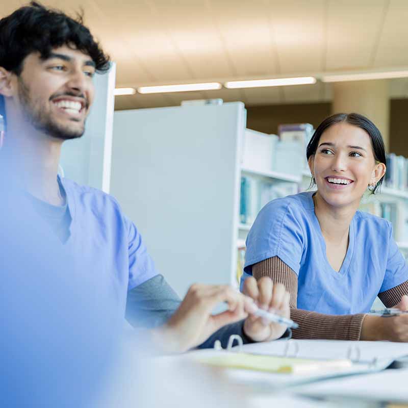 Two nurses smiling during a meeting.